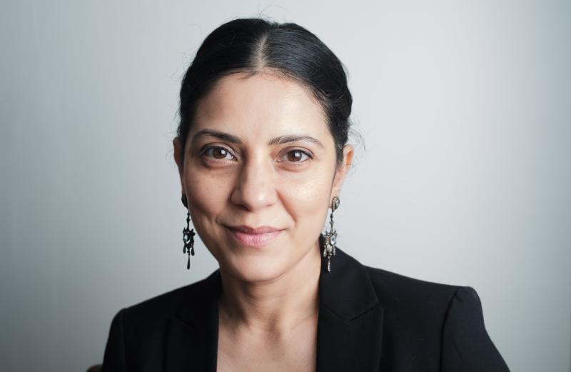 Image of a woman in a black suit smiling at the camera